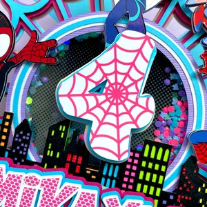 May include: A pink and white cake topper with a spiderweb design. The topper features a pink number four, a spiderweb design, and a cityscape. The cake topper also includes the name "KAYLA" in pink letters.