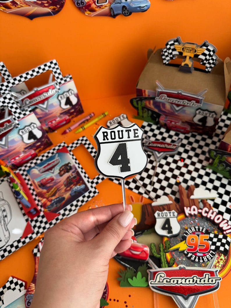 Pode incluir: Um conjunto de decora&ccedil;&atilde;o de festa tem&aacute;tica de Cars com um padr&atilde;o de xadrez preto e branco. O conjunto inclui uma placa que diz "Rota 4", uma placa que diz "Ka-Chow!" com um raio e o n&uacute;mero 95, e uma placa que diz "Leonardo" com um gr&aacute;fico de carro vermelho.