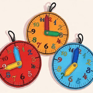 Könnte beinhalten: Drei kreisförmige, uhrförmige Ornamente mit leuchtend roten, orangefarbenen und blauen Stoffzifferblättern. Jede Uhr hat bunte gestickte Zahlen von eins bis zwölf, schwarze Strichmarkierungen und zwei bewegliche Zeiger mit einem Metallniet.
