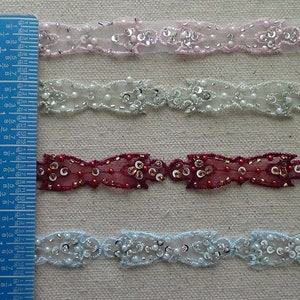 May include: Four different colors of beaded trim with a scalloped edge. The trim is approximately 1 inch wide and is shown next to a ruler.