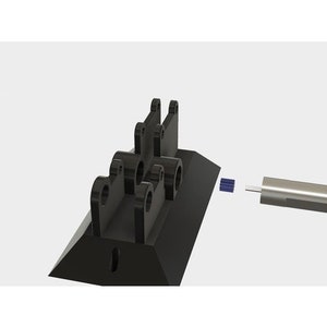 May include: A black plastic 3D printed motor mount with a small silver motor attached to it. The motor mount has a triangular base and a series of holes for mounting the motor.