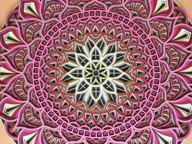 K&ouml;nnte beinhalten: Ein mehrschichtiges Mandala-Kunstwerk in Rosa, Rot, Schwarz, Wei&szlig; und Gold. Das detaillierte Design zeigt ein zentrales Blumenmuster, das von konzentrischen geometrischen Formen umgeben ist. Dieses dekorative Kunstwerk eignet sich f&uuml;r die Wanddekoration.