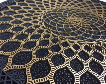 May include: A circular wooden wall art piece with a geometric design. The centre of the piece features a gold-coloured mandala with a black background. The outer portion of the piece features a black background with a gold-coloured geometric pattern.