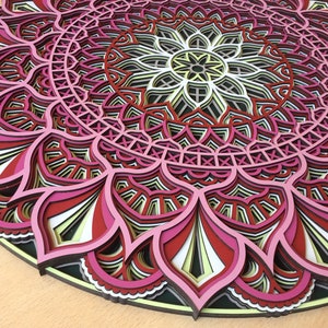 K&ouml;nnte beinhalten: Mehrschichtiges Holz-Mandala in Rosa, Rot, Schwarz, Wei&szlig; und Gelb. Das kreisf&ouml;rmige Design weist florale und geometrische Muster auf. Dieses dekorative St&uuml;ck eignet sich f&uuml;r Wandkunst und hat einen Durchmesser von ca. 30 cm.