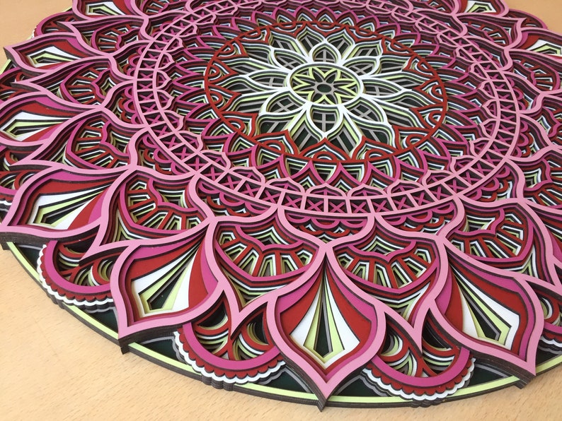 K&ouml;nnte beinhalten: Mehrschichtiges Holz-Mandala in Rosa, Rot, Schwarz, Wei&szlig; und Gelb. Das kreisf&ouml;rmige Design weist florale und geometrische Muster auf. Dieses dekorative St&uuml;ck eignet sich f&uuml;r Wandkunst und hat einen Durchmesser von ca. 30 cm.