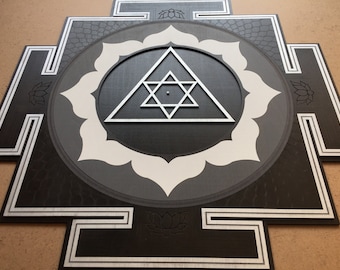 May include: A black and white mandala with a silver geometric design in the center. The mandala is surrounded by a black square with a white border.