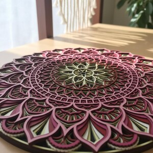 K&ouml;nnte beinhalten: Mehrschichtiges Holzmandala in Burgunder-, Rosa- und Cremet&ouml;nen. Das komplizierte kreisf&ouml;rmige Design weist detaillierte Ausschnitte auf. Das Mandala wird auf einer hellbraunen Oberfl&auml;che pr&auml;sentiert und zeigt seine Tiefe und Handwerkskunst.
