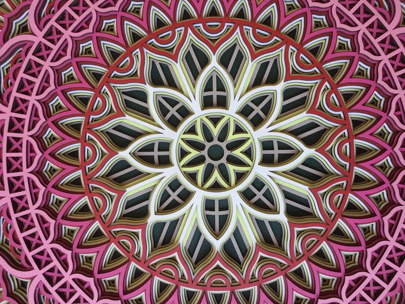 K&ouml;nnte beinhalten: Ein mehrschichtiges Papierkunstwerk mit einem symmetrischen floralen Design. Das Kunstwerk zeigt ein Mandala-&auml;hnliches Muster mit konzentrischen Kreisen in Rosa-, Rot-, Gelb- und Gr&uuml;nt&ouml;nen. Das komplizierte Design stellt eine Blume dar.