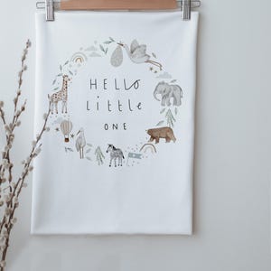 Puede incluir: Manta de bebé blanca con una ilustración de acuarela de animales en un círculo. El texto "HELLO little ONE" está en el centro del círculo.
