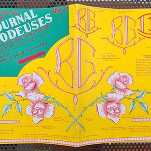 May include: Open magazine spread with a yellow and green cover. The cover features text in French, including "LE JOURNAL DES BRODEUSES." Pink roses and decorative elements adorn the pages. The magazine is a guide for embroidery.