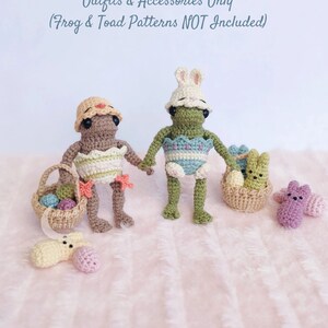 Może przedstawiać: Dwie postaci amigurumi wykonane na szydełku, jedna z żółtym kapeluszem kurczaka, a druga z białym kapeluszem królika, trzymające koszyki z kolorowymi jajkami wielkanocnymi. Postacie są ubrane w szydełkowe stroje i stoją na różowym, puszystym podłożu. Outfits & Accessories Only (Frog & Toad Patterns NOT Included)