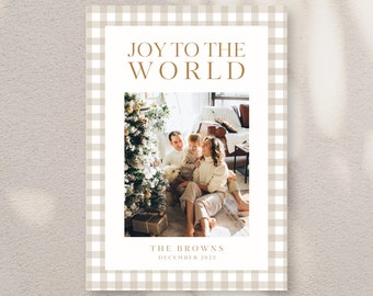 May include: A Christmas card with a gingham pattern border. The card features a photo of a family with a Christmas tree and the text "Joy to the World". The family's last name is "The Browns" and the year is "December 2023".