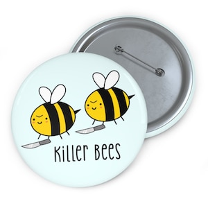 May include: A white button with a blue background features two cartoon bees holding knives. The text "Killer Bees" is printed below the bees.
