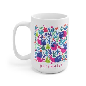 Puede incluir: Taza de cer&aacute;mica blanca con una ilustraci&oacute;n colorida de gatos vestidos de sirenas. La ilustraci&oacute;n incluye colores rosa, azul, verde y rojo. El texto "purrmaids" est&aacute; impreso en rosa en la parte inferior de la taza.