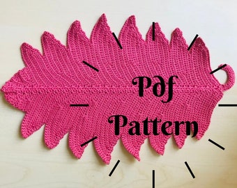 May include: A pink crocheted leaf-shaped pot holder with a loop handle. The text "Pdf Pattern" is written on the pot holder.