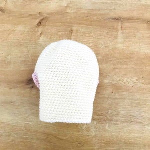 Peut inclure: Chapeau crochet&eacute; blanc avec une bordure rose.