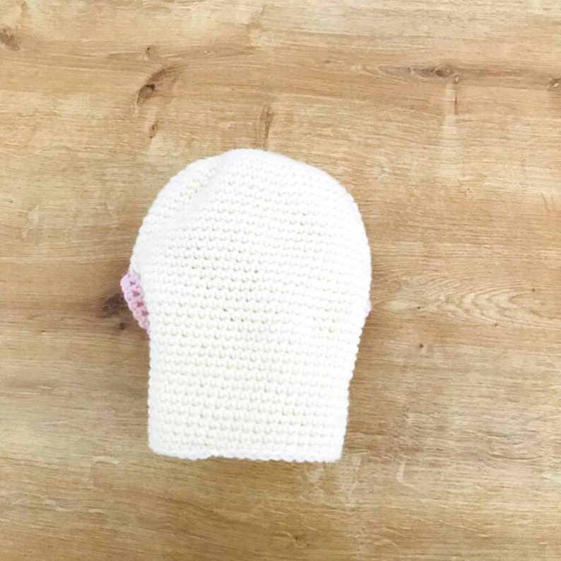 Peut inclure: Chapeau crochet&eacute; blanc avec une bordure rose.