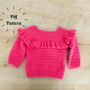 Pode incluir: Um suéter rosa de crochê com uma gola de babados. O suéter tem mangas compridas e um caimento solto. O texto "Pdf Pattern" é visível no canto superior esquerdo da imagem.