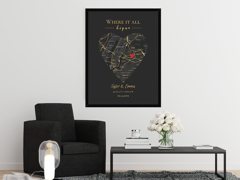 May include: A black and gold framed print with a heart-shaped map of a city. The map is outlined in gold and has a red heart in the center. The text "Where it all began" is at the top of the print, and the names "Tyler & Emma" and a date are at the bottom.