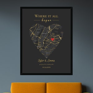 May include: A black and gold print with a heart-shaped map of a city. The text "Where it all began" is at the top of the print. The text "Tyler & Emma" is at the bottom of the print, along with coordinates and a date.
