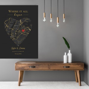 May include: A black and gold map of a city in the shape of a heart with a red heart in the center. The text "Where it all began" is at the top of the map. The names "Tyler & Emma" and a date are at the bottom of the map.