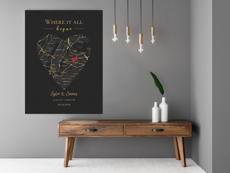 May include: A black and gold map of a city in the shape of a heart with a red heart in the center. The text "Where it all began" is at the top of the map. The names "Tyler & Emma" and a date are at the bottom of the map.