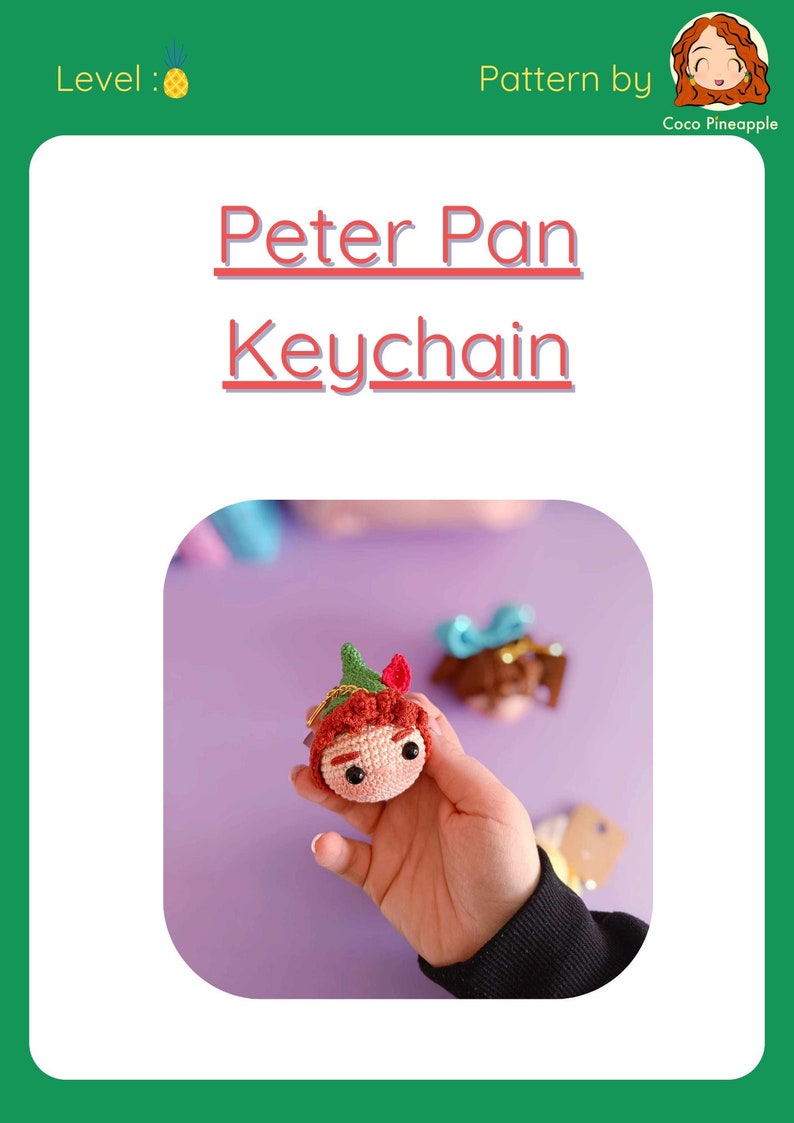 May include: Crocheted Peter Pan keychain with a green hat, red hair, and brown eyes. The keychain is held in a hand against a purple background.