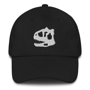 Op de afbeelding: Zwarte baseballpet met een wit geborduurd dinosaurus schedel ontwerp.