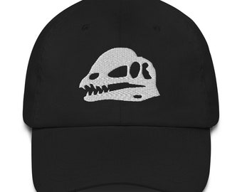 May include: A black baseball cap with a white embroidered dinosaur skull design.