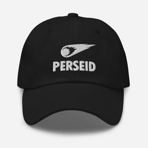 Peut inclure: Une casquette de baseball noire avec une broderie blanche sur le devant. Le motif comprend un graphique stylisé de comète ou de météore avec une traînée, placé au-dessus du mot PERSEID en lettres brodées blanches, grasses et majuscules.
