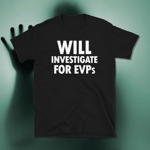 May include: A black short-sleeved t-shirt featuring the white text WILL INVESTIGATE FOR EVPs printed in a bold, sans-serif font across the centre of the chest. The garment has a crew neckline and a standard fit with straight hemmed sleeves.