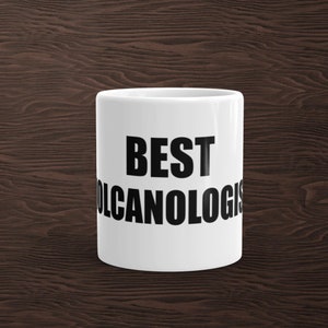 May include: White ceramic coffee mug with black text that reads "BEST VOLCANOLOGIST".