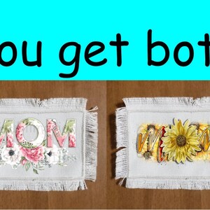 May include: Two white fabric coasters with frayed edges. One coaster features the word "MOM" in pink and white letters with floral accents. The other coaster features the word "MOM" in yellow letters with a sunflower in the centre.