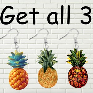 Può includere: Tre paia di orecchini a forma di ananas. Gli ananas sono in stili diversi: uno è blu e giallo, uno è verde e giallo e uno è rosso e arancione.