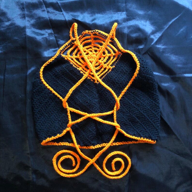 May include: A black crochet top with orange straps and a crocheted design. The straps are tied at the back.
