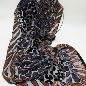 May include: A brown, black and grey patterned scarf with a zebra, leopard and cheetah print.