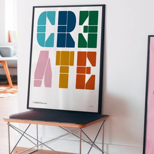 Peut inclure: Une affiche murale rectangulaire encadrée présentant le mot CREATE en grandes lettres colorées et géométriques. Les lettres sont composées de formes plus petites dans des tons de bleu sarcelle, bleu marine, vert foncé, rose pâle, or et orange brûlé.