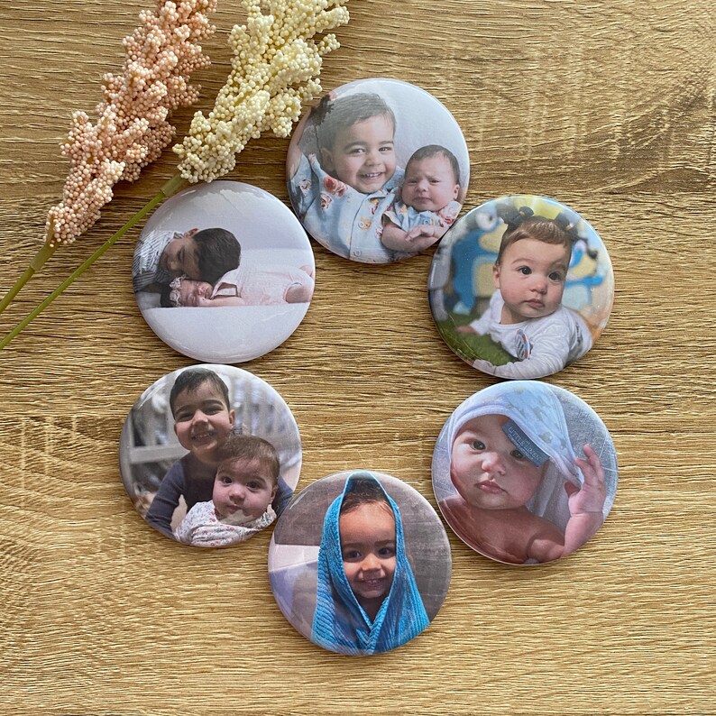 May include: Six round button badges with images of children. The badges are white with a silver border. The images are of children of different ages and ethnicities. Some of the children are smiling, while others are looking at the camera.