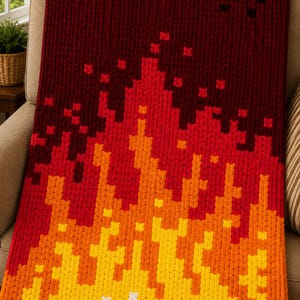 May include: A chunky knit blanket featuring a pixelated flame pattern that transitions from white at the bottom to yellow, orange, red, and deep burgundy at the top. The texture is thick and soft, created with a repeating stitch pattern.
