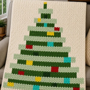Könnte beinhalten: Eine cremefarbene, grob gestrickte Decke mit einem großen, mittig platzierten Weihnachtsbaum-Design. Der Baum besteht aus horizontalen Reihen aus hellgrünem und dunkelgrünem Garn, akzentuiert durch kleine, quadratische rote, gelbe und blaue Verzierungen.