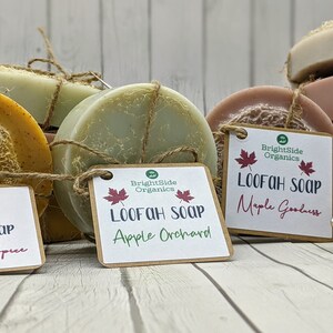 Może przedstawiać: Cztery okrągłe kostki ręcznie robionego mydła owinięte sznurkiem i oznaczone tekstem "BrightSide Organics" oraz zapachem każdego mydła: "Pumpkin Spice", "Apple Orchard", "Maple Goodness" i "Warm Vanilla".