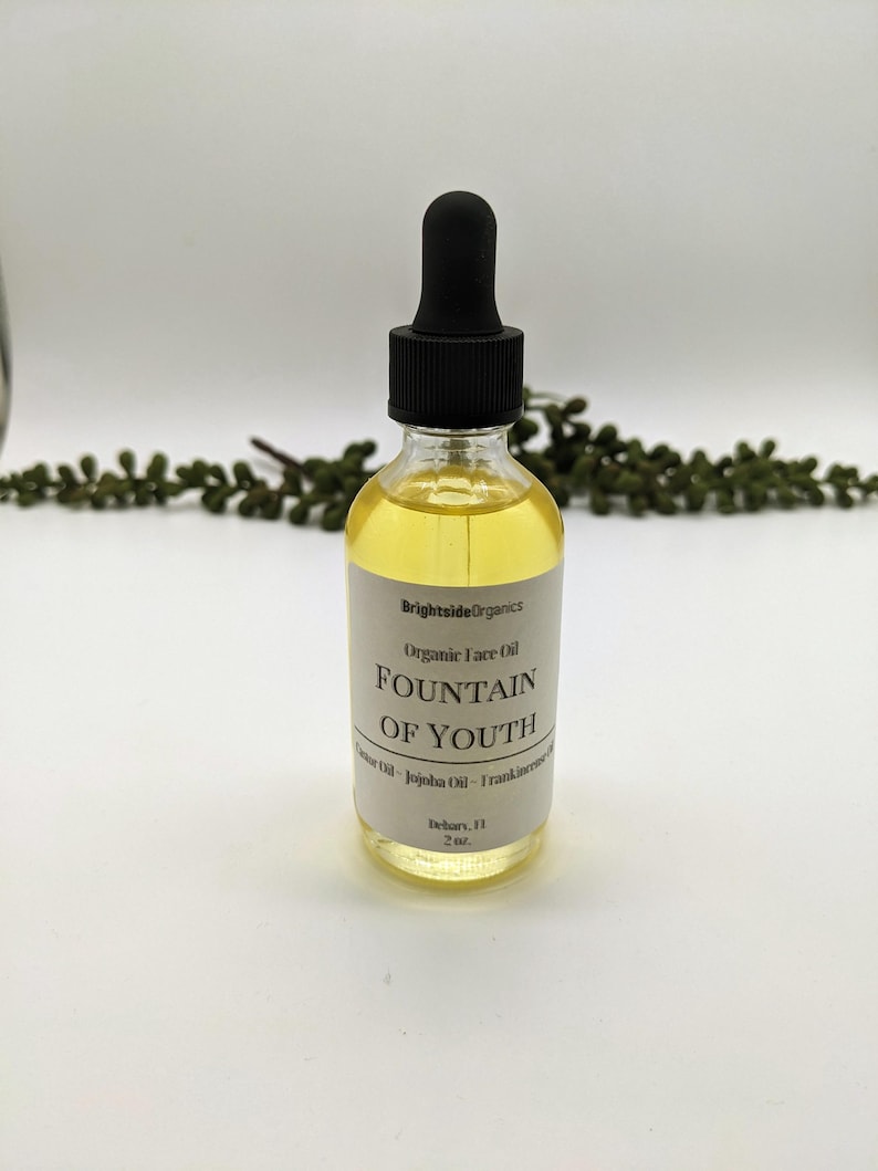 May include: A clear glass bottle with a black dropper top and a white label that reads "Brightside Organics Organic Face Oil FOUNTAIN OF YOUTH Jojoba Oil - Frankincense" and "Delray, FL 2 oz."