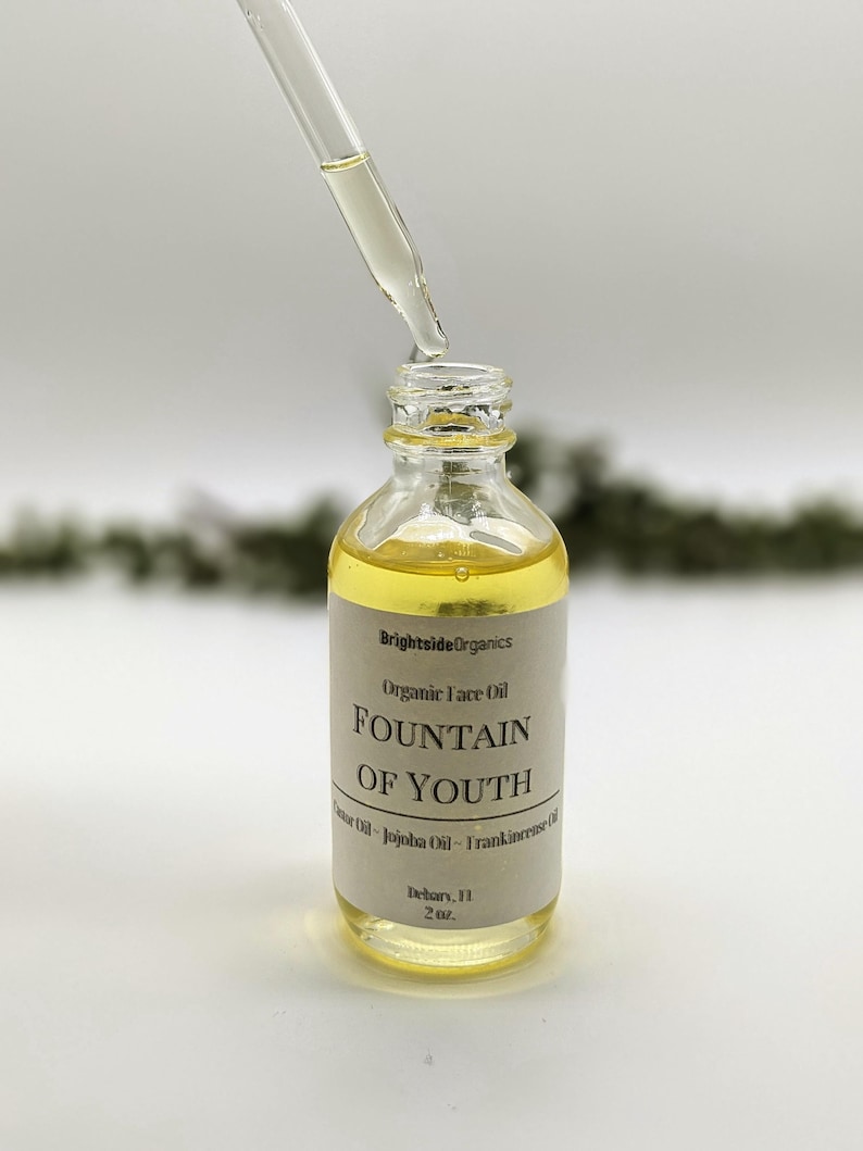May include: A clear glass bottle with a dropper filled with a yellow liquid. The bottle has a label that reads "Brightside Organics Organic Face Oil FOUNTAIN OF YOUTH Castor Oil - Jojoba Oil - Frankincense Oil Delray, FL 2 oz."