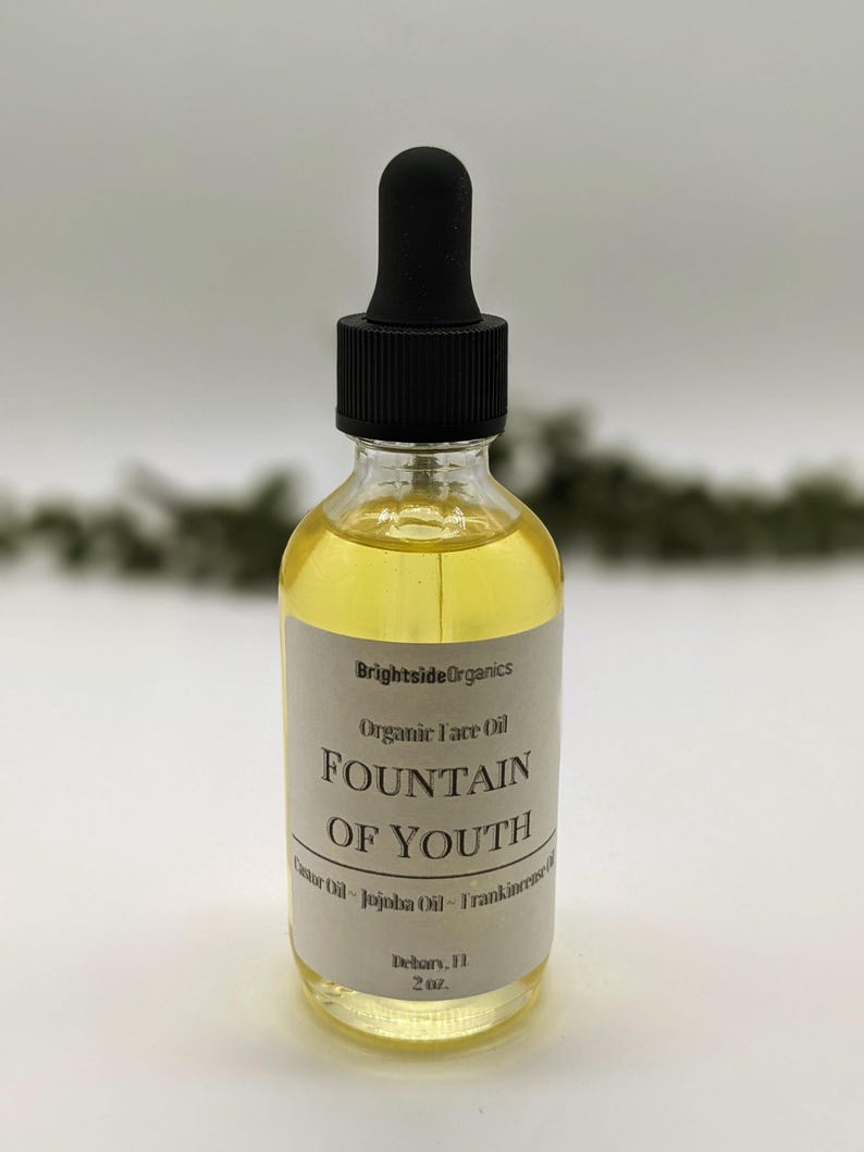 May include: A clear glass bottle with a black dropper top filled with a yellow liquid. The label reads "Brightside Organics Organic Face Oil Fountain of Youth Castor Oil - Jojoba Oil - Frankincense Oil Debary, FL 2 oz."