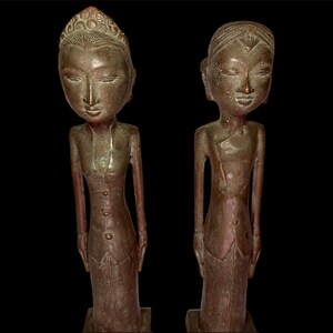 Puede incluir: Dos estatuas de bronce de personas de pie una al lado de la otra. Las estatuas llevan ropa tradicional y tienen rasgos faciales detallados.