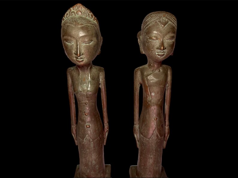 Puede incluir: Dos estatuas de bronce de personas de pie una al lado de la otra. Las estatuas llevan ropa tradicional y tienen rasgos faciales detallados.