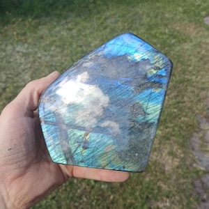 May include: A large, iridescent blue labradorite crystal with a smooth, polished surface. The crystal has a unique, natural pattern of striations and inclusions.