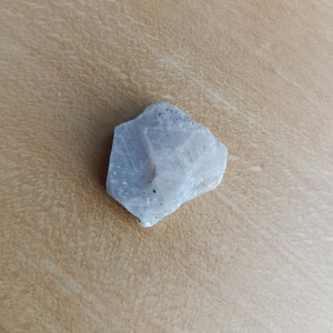 Puede incluir: Un cristal blanco opaco de forma irregular con una superficie rugosa y texturizada.