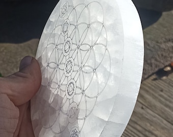 May include: White selenite charging plate with a flower of life design and seven chakra symbols etched on the surface.