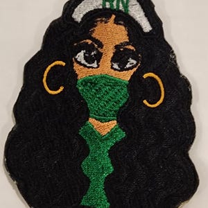 May include: Embroidered patch featuring a stylized nurse with dark hair, wearing a green face mask and a white cap with "RN" in green. The nurse has gold hoop earrings. The patch is black with a scalloped edge.